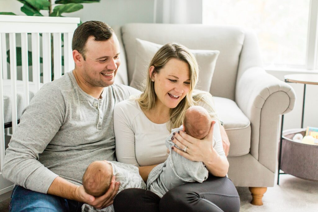 Mom and dad holding twin babies in nursery