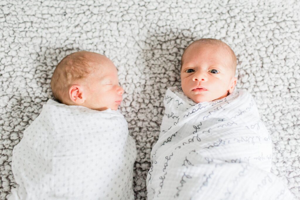 Newborn twins laying next to each other swaddled