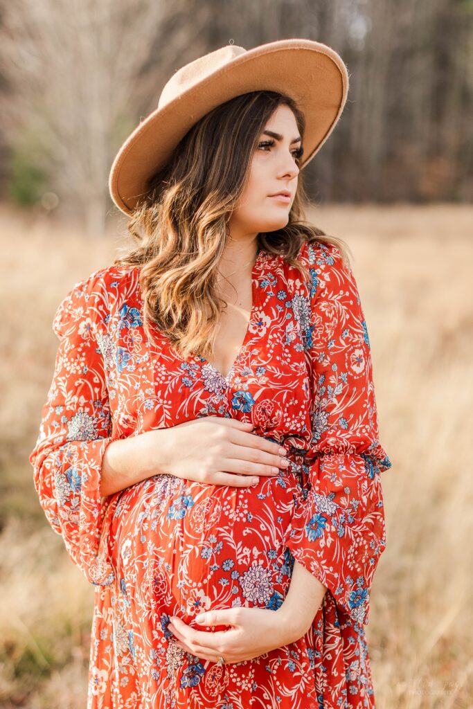 Pregnant woman in field wearing hat