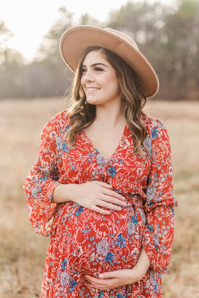 Pregnant woman standing in a field at sunset