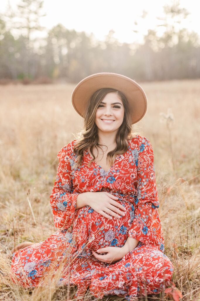 Pregnant woman sitting in a field at sunset