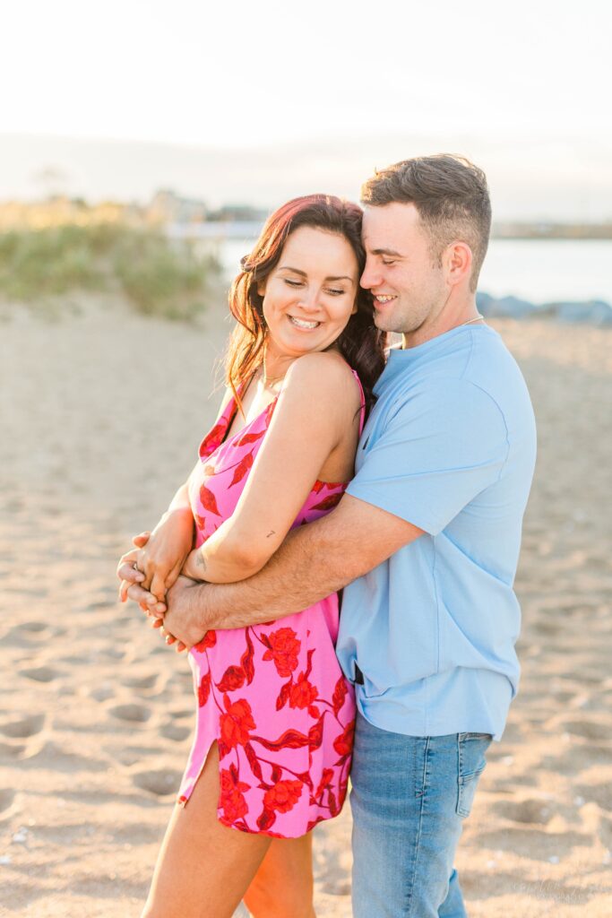 Couple snuggled together on beach at Plum Island