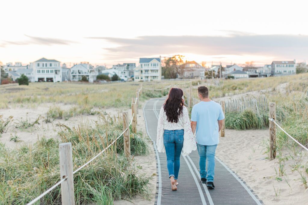 Man and woman walking together down boardwalk at Plum Island beach