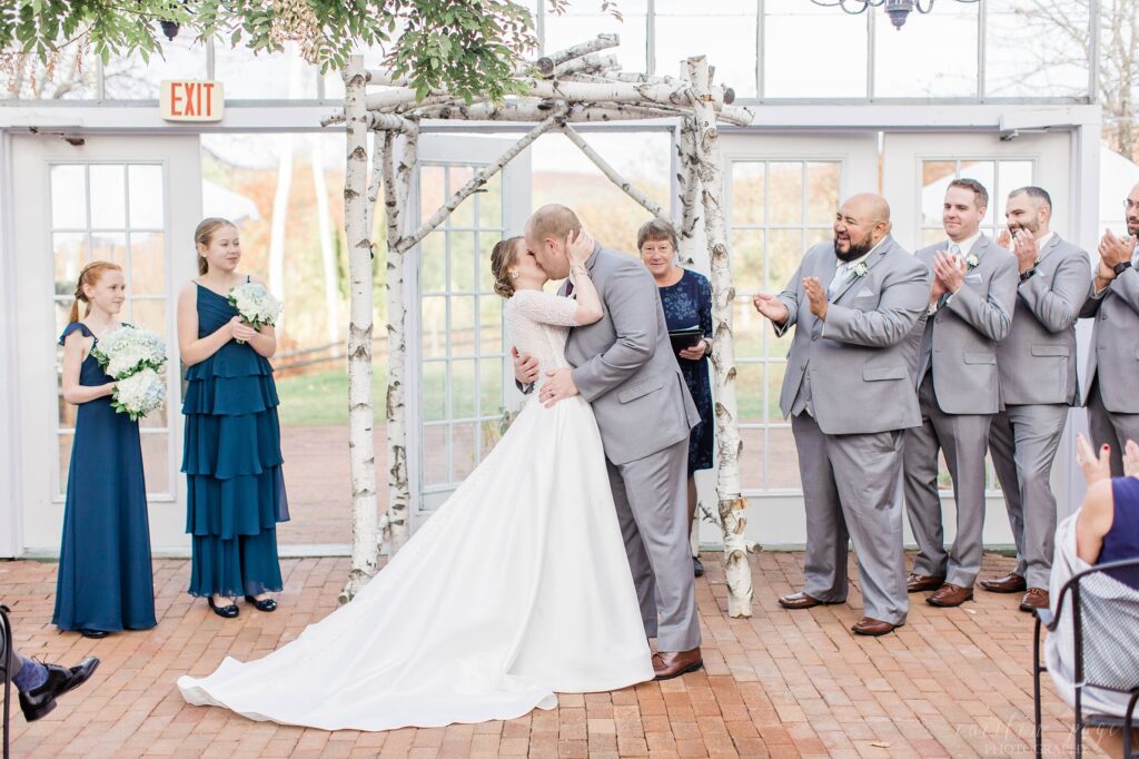 Bride and groom first kiss at wedding ceremony in greenhouse
