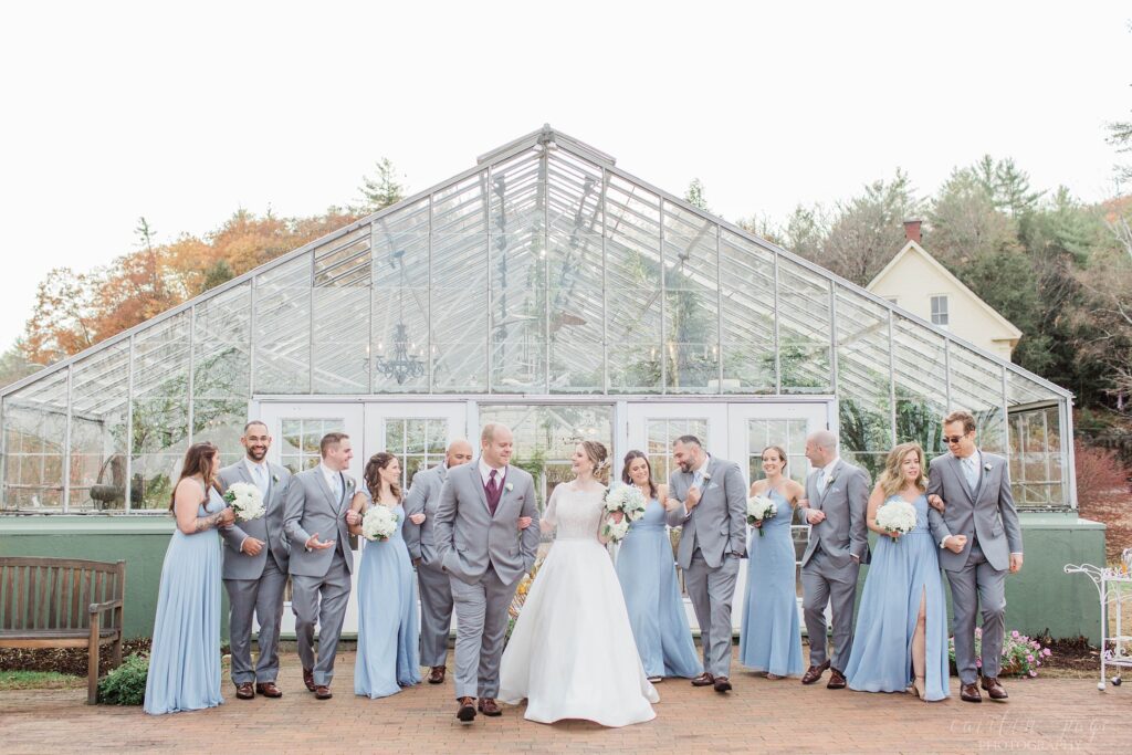 Bridal party standing together in front of greenhouse