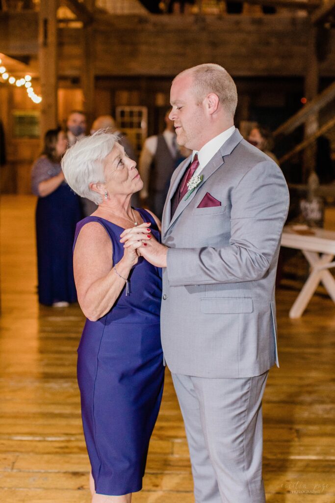 Groom & his mom dancing in barn at wedding reception