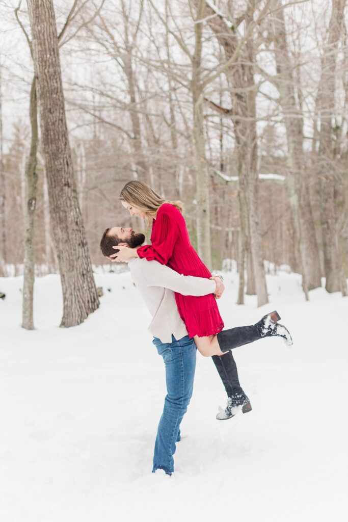 Man lifting woman in the air at snowy session