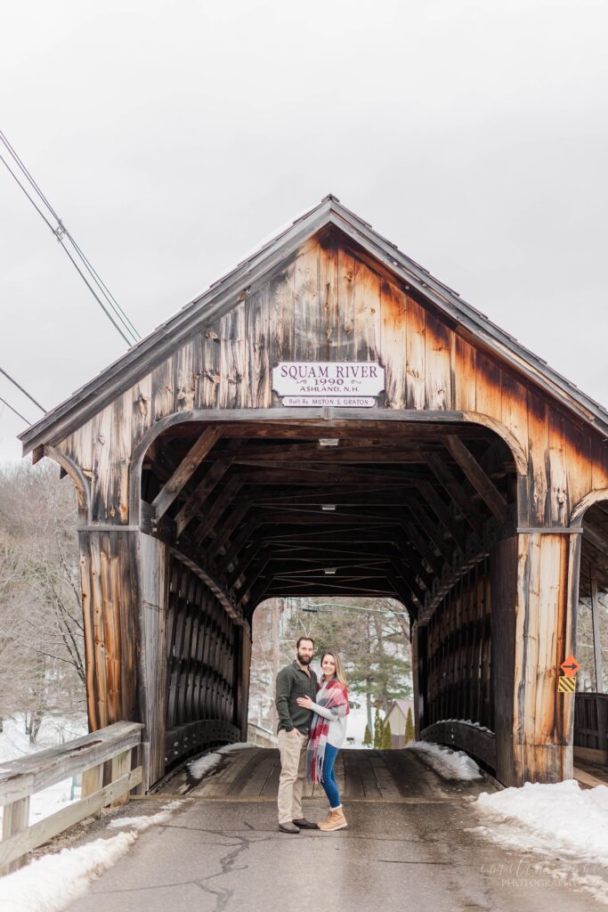 Couple standing in front of Squam Lake covered bridge