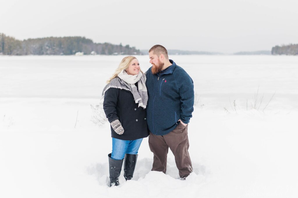 Couple standing in the snow next to a frozen lake