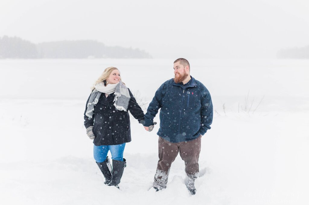 Man and woman standing in the snow together at winter proposal