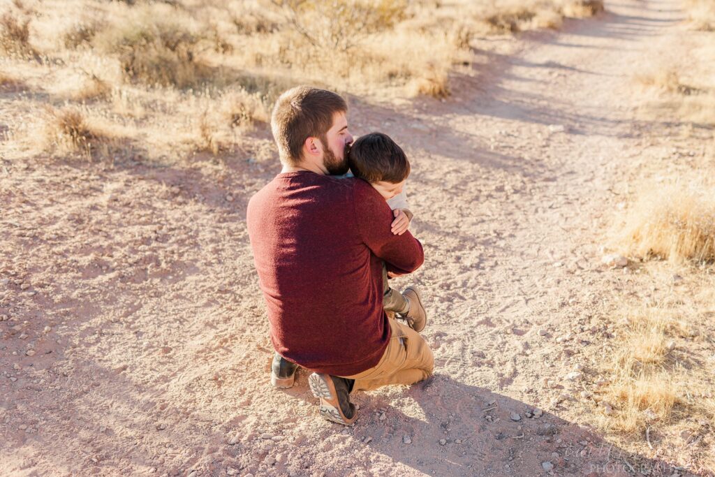 Little boy hugging his dad in the desert