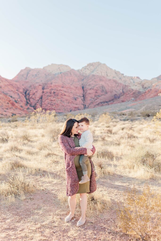 Pregnant woman holding toddler boy in the desert