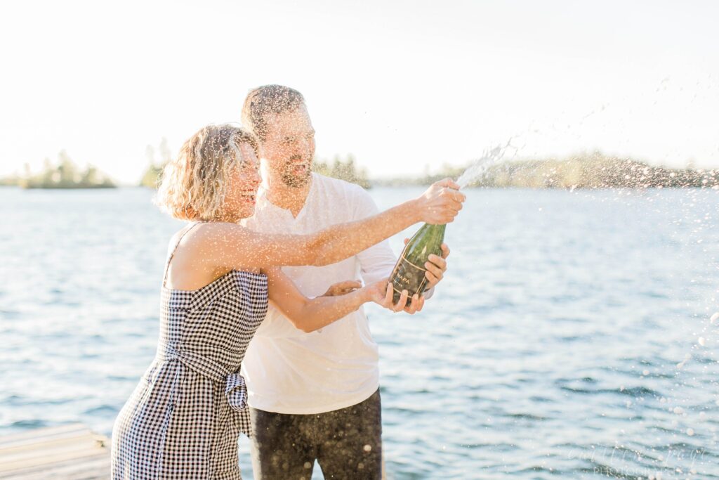 Couple popping champagne on a dock