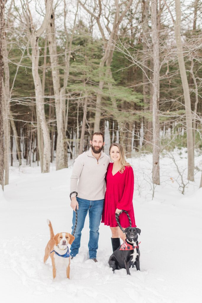 Couple standing together with their dogs in the snow