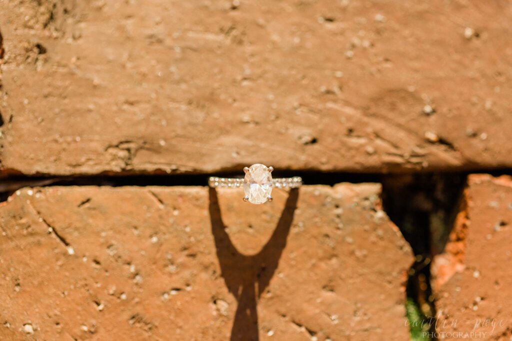 Oval solitaire engagement ring wedged in bricks