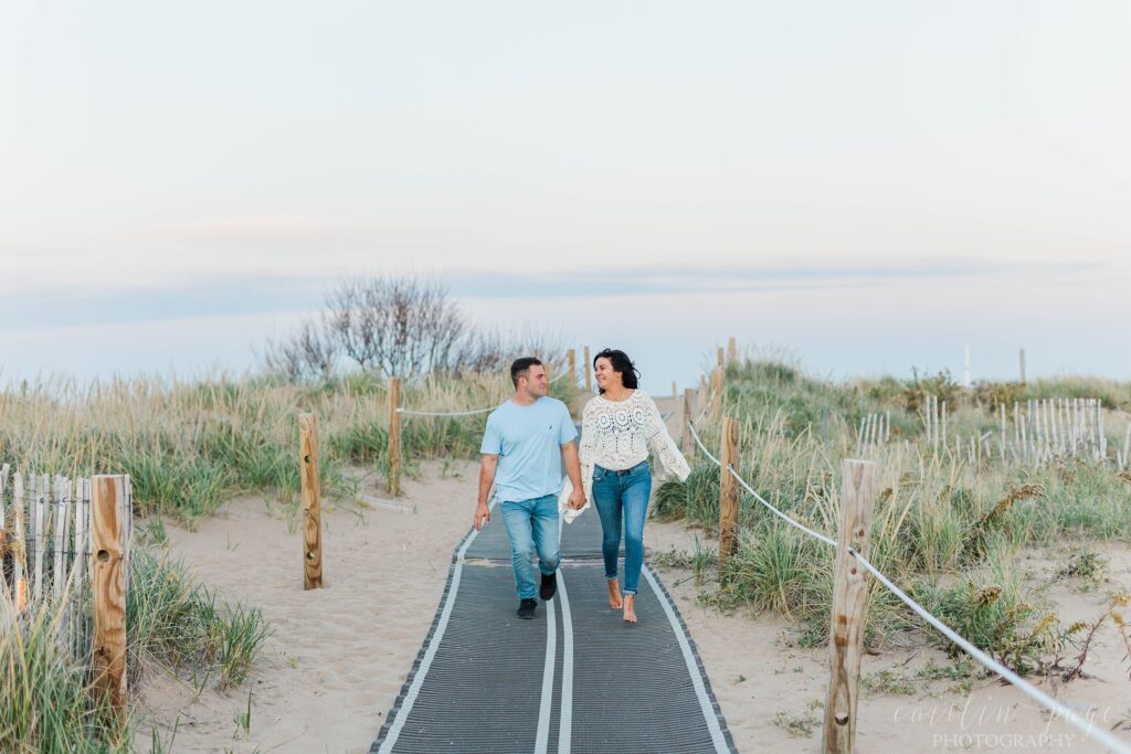 Couple running down beach boardwalk at sunset