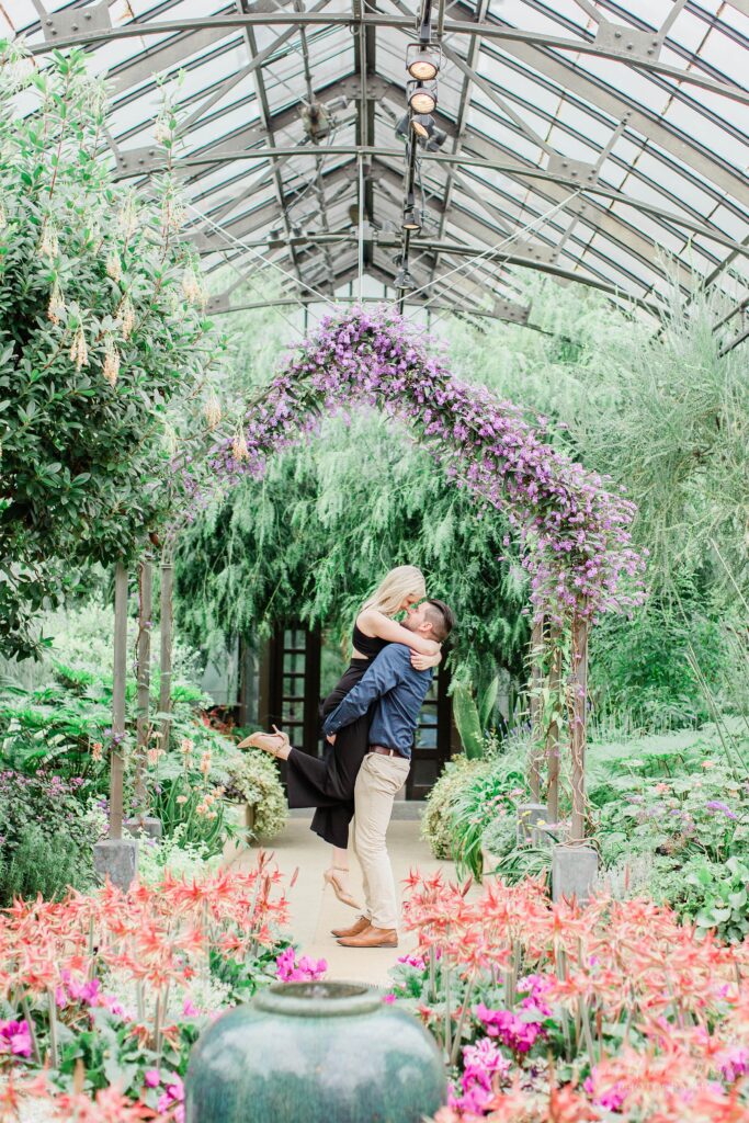 Man picking woman up in front of floral arch at Longwood Gardens