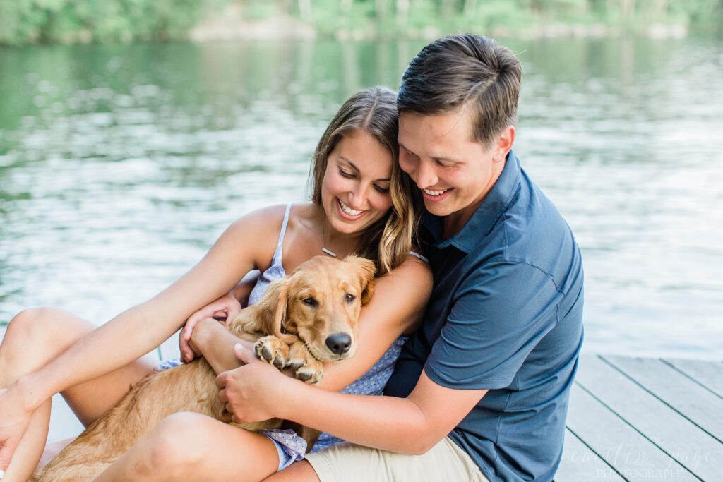 Man and woman snuggling puppy in front of water
