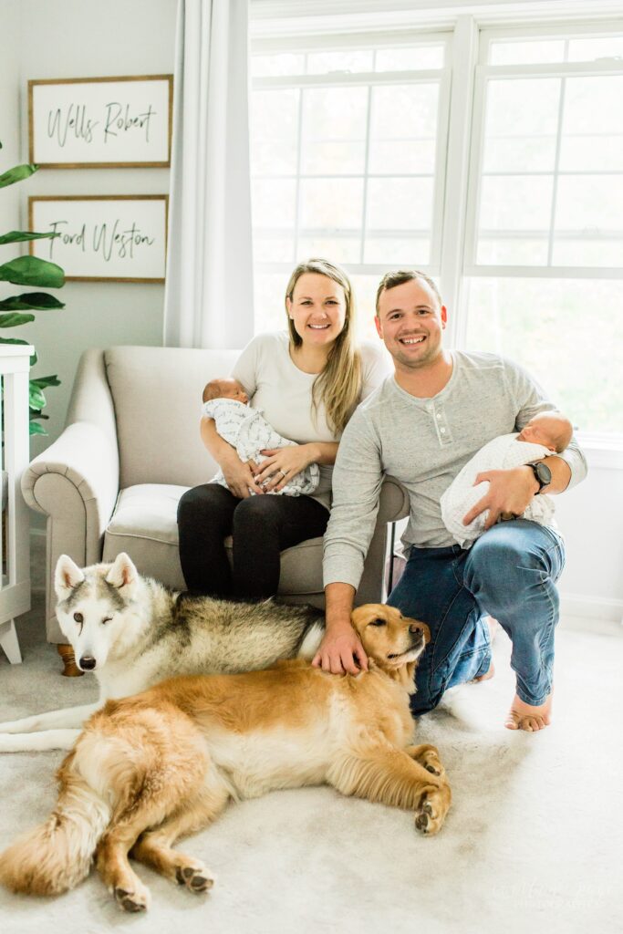 Parents sitting with twin newborn babies and dogs