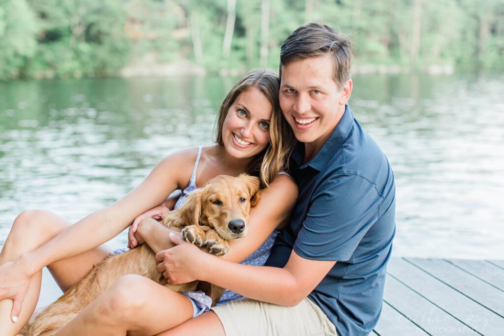 Couple sitting on dock holding puppy in their arms