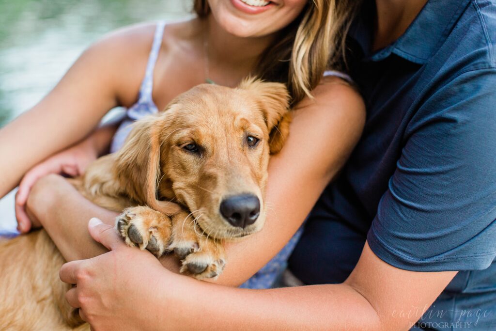 Couple sitting on dock holding puppy in their arms