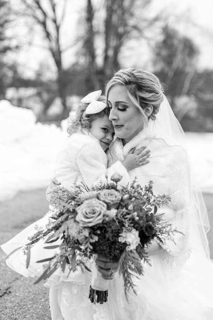 Black and white photo of bride hugging flower girl