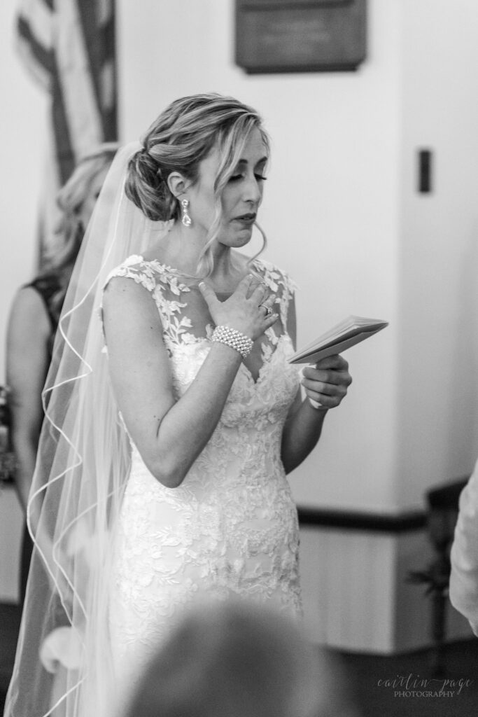 Black and white image of bride reading her vows to groom
