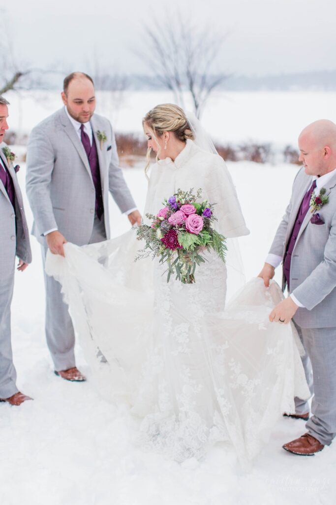 Groomsmen helping bride with her dress