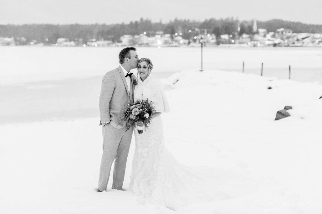 Bride and groom standing in front of town in the snow