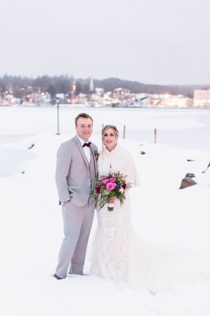 Bride and groom standing in front of town in the snow