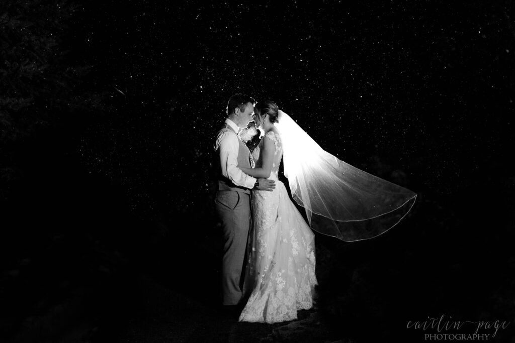 Black and white image of bride and groom standing in the snow