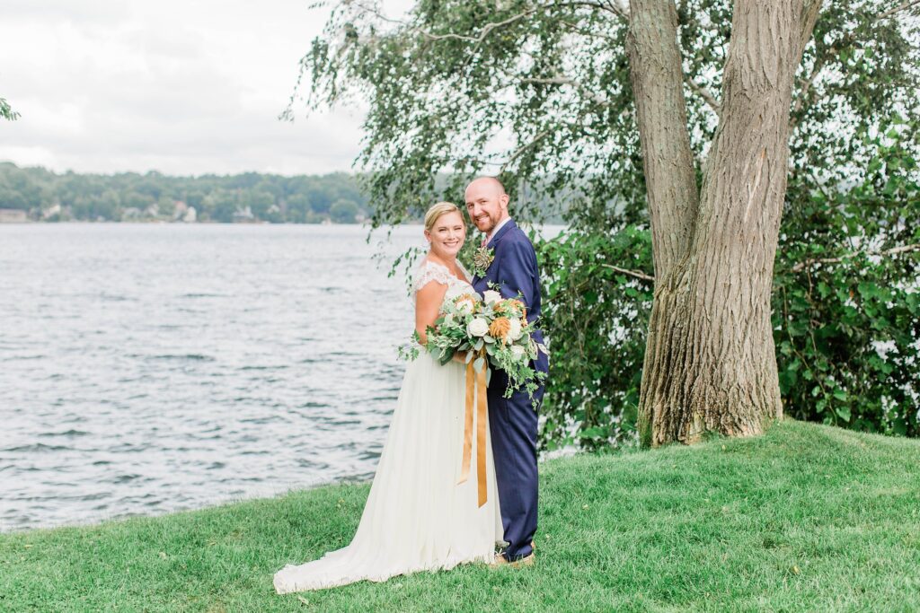 Bride and groom standing together in front of lake