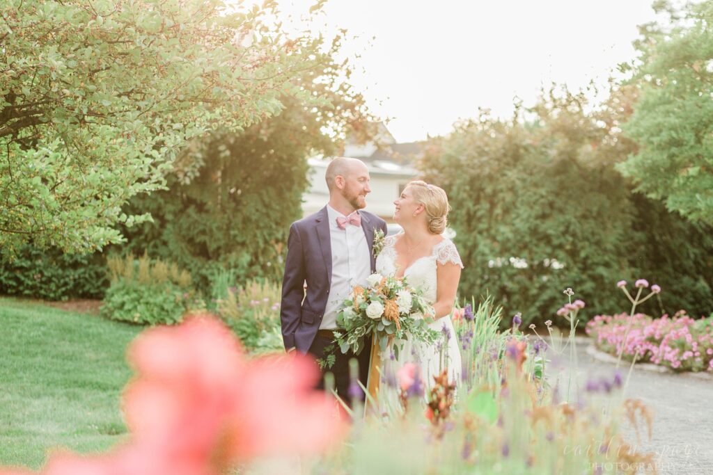 Bride and groom standing outside in flower beds