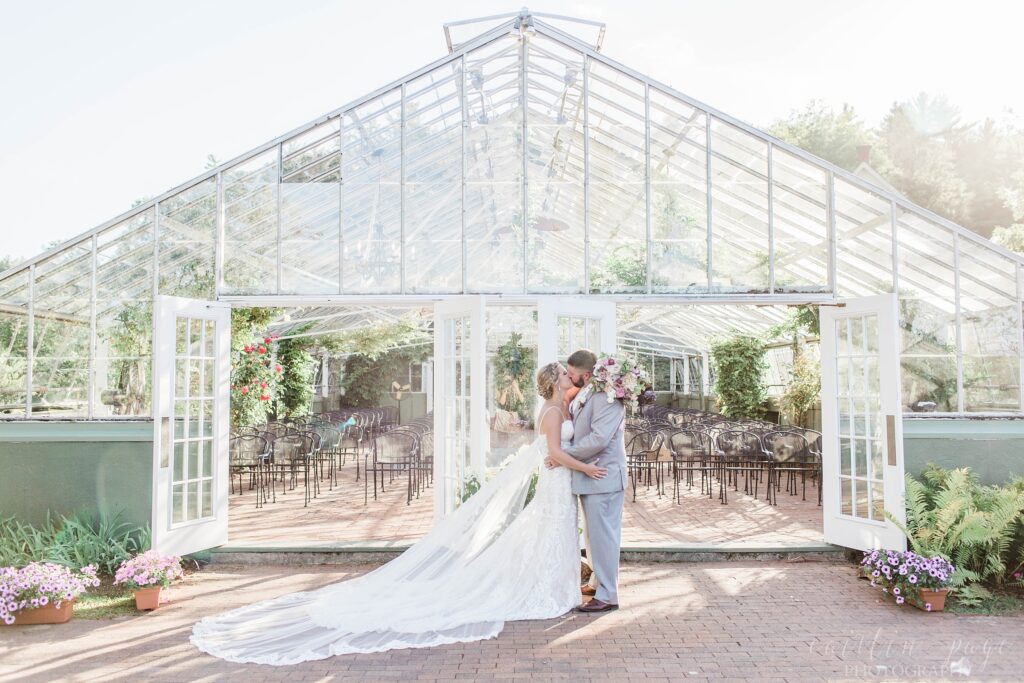 Bride and groom standing in front of greenhouse