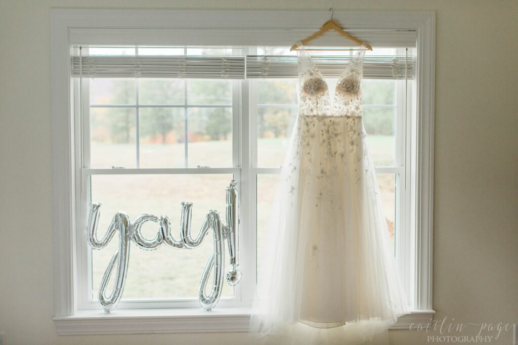 Wedding dress hanging in window with balloon