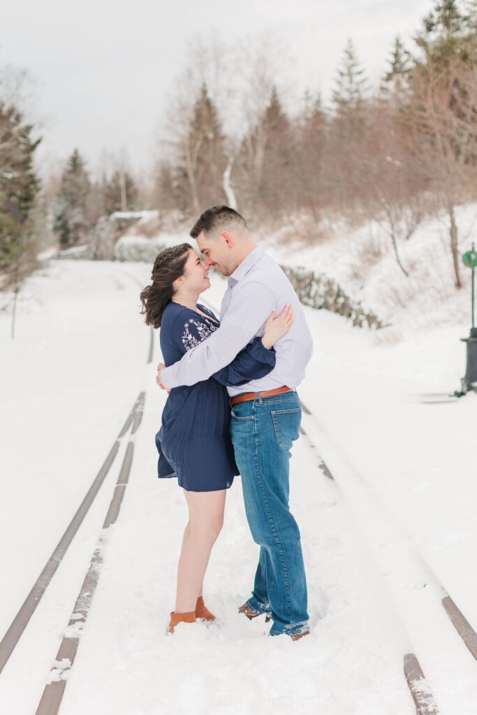 Couple nuzzling together at winter engagement session