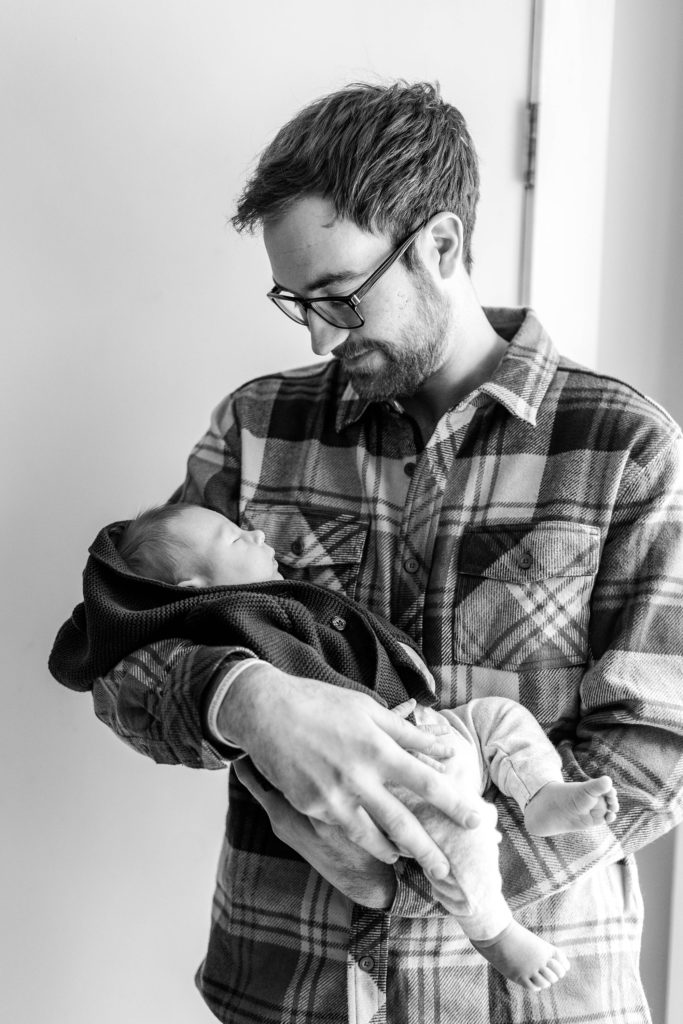 Dad holding newborn baby boy at winter newborn session