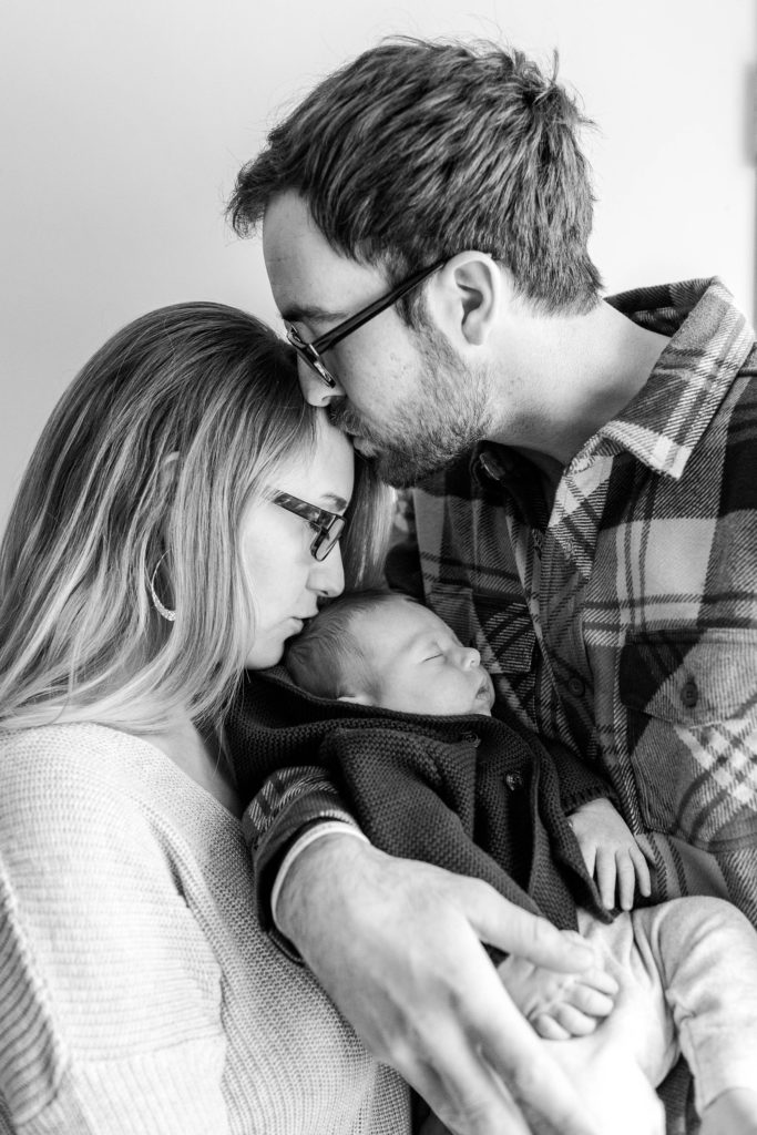Dad kissing mom on the head as she kisses baby boy