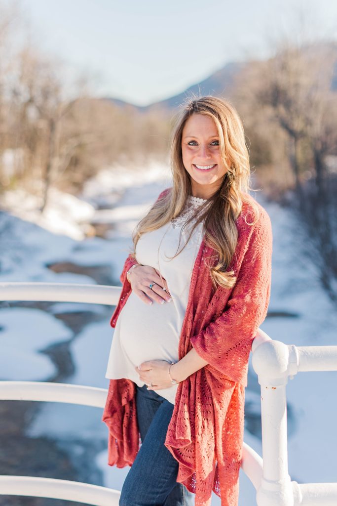 Pregnant woman standing on bridge over wintry river