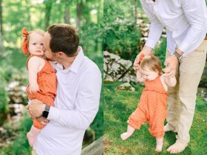Father helping his baby daughter take steps on the grass, holding her hands for support. Dad kissing baby girl’s cheek while holding her in the forest, both dressed in warm tones.