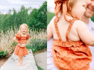 Blonde toddler in a ruffled orange outfit smiling confidently while standing barefoot on a stone wall. Close-up of a baby girl in a textured orange romper and bow, being held by her smiling dad.