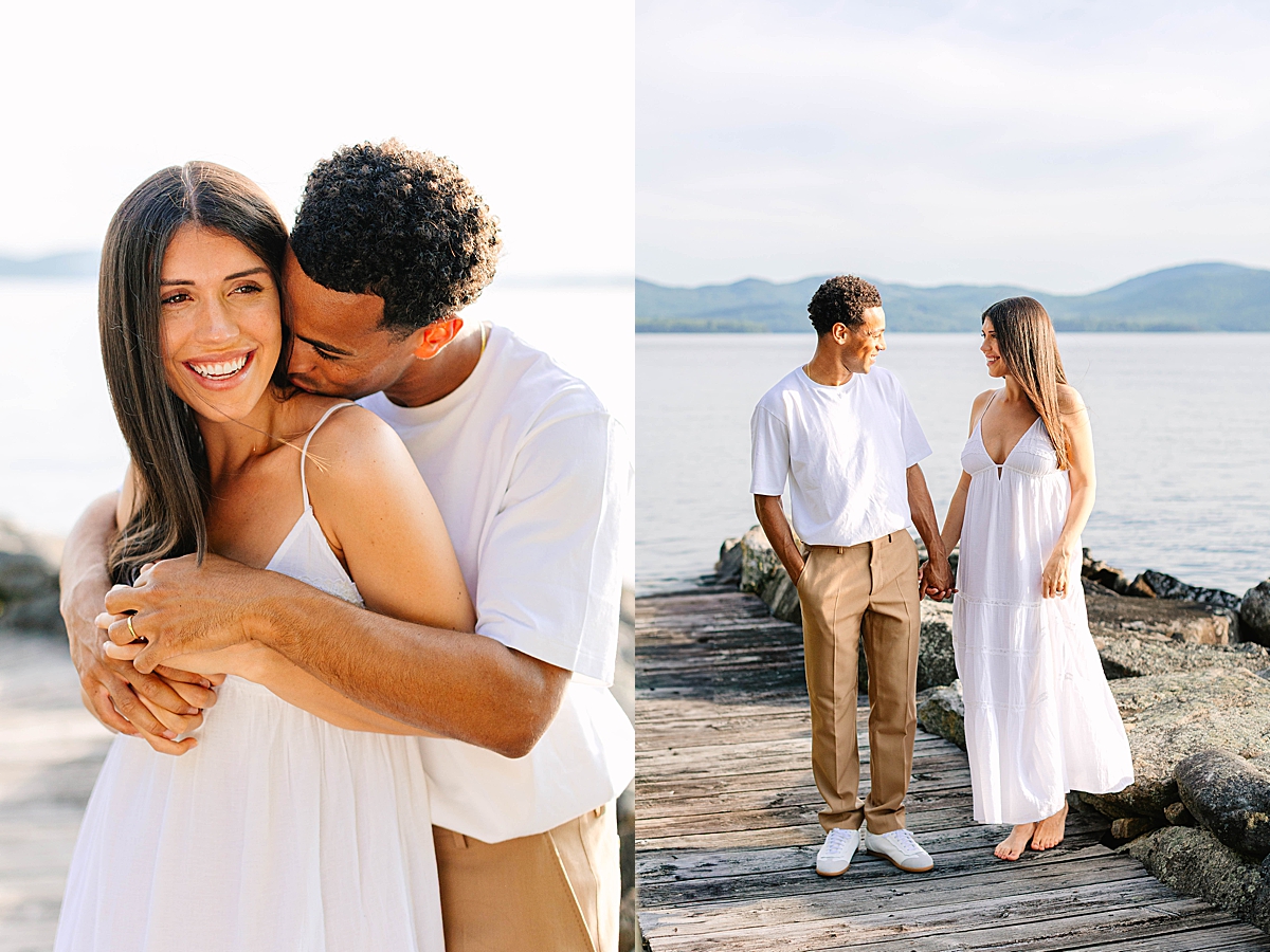 Man embracing a smiling woman from behind and kissing her shoulder, standing on a lakeside dock.